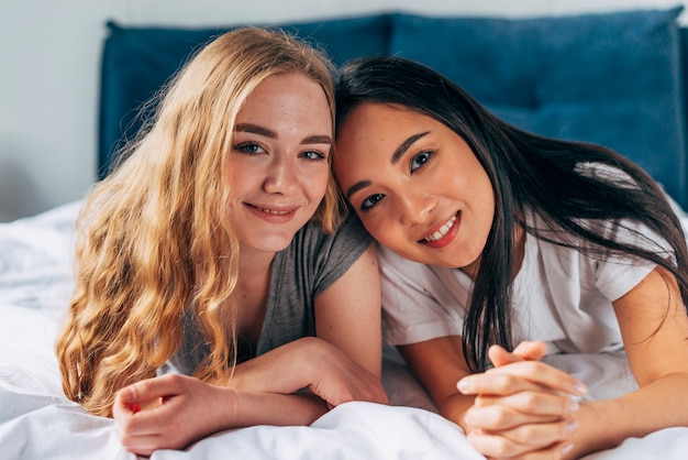 Female friends on bed looking at camera