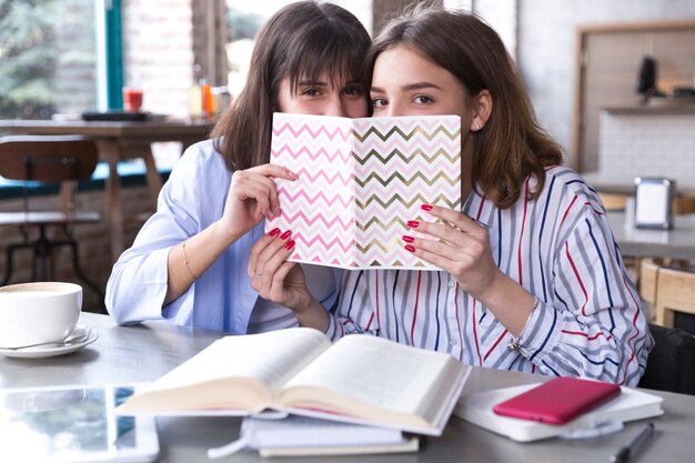 Free photo female friends in cafe with copybook