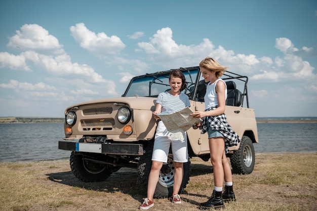 Female friends checking map while traveling by car