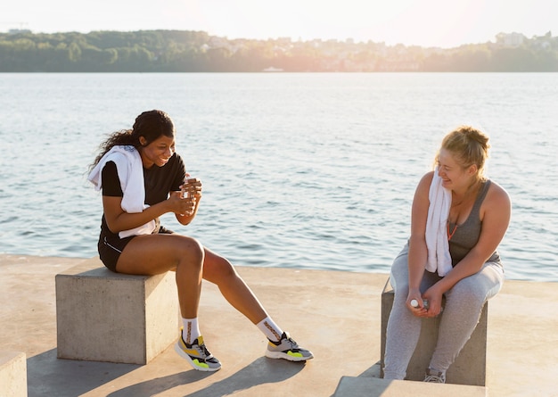 Female friends conversing after working out by the lake