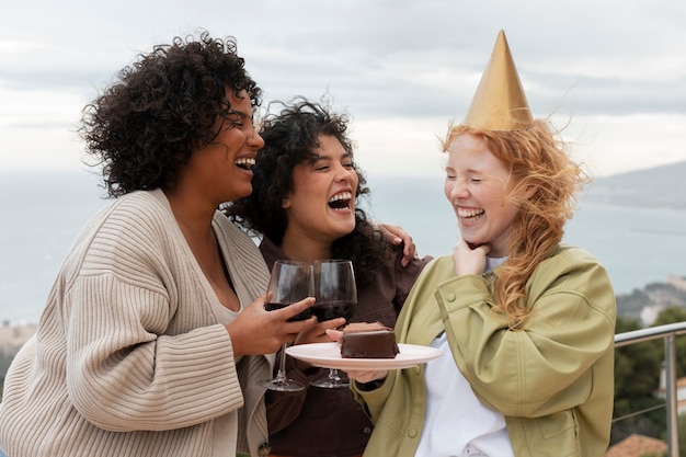 Foto gratuita amici femminili che mangiano torta e bevono vino durante la festa all'aperto