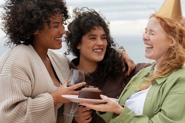 Female friends eating cake and drinking wine during outdoor party