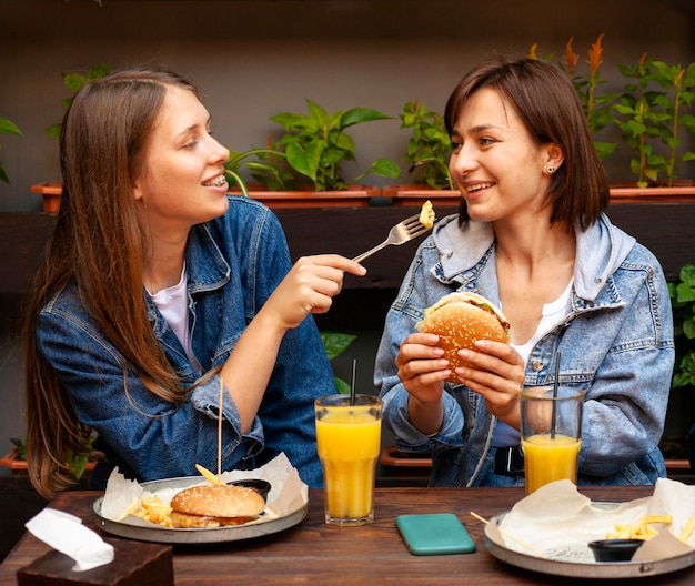 Free photo female friends feeding each other burgers