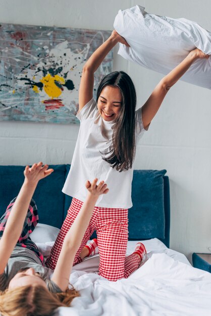 Female friends fighting by pillows