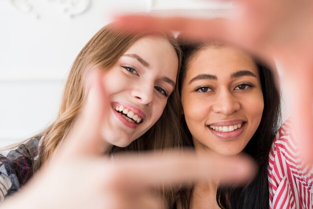 Female friends gesturing selfie at camera