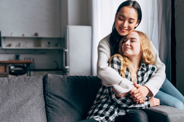 Female friends hugging tenderly at home