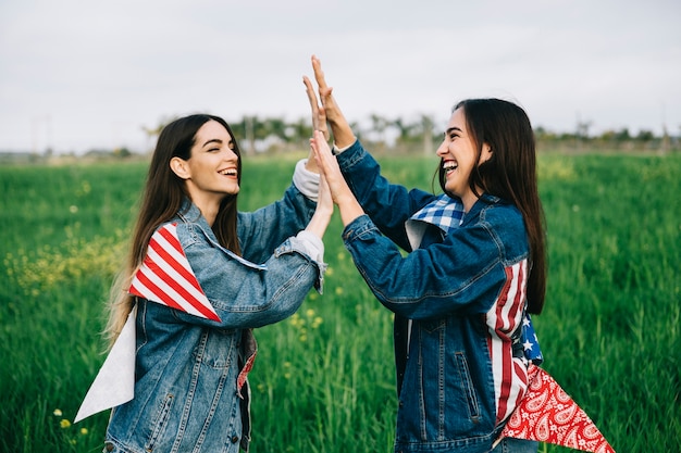 Amici femminili che ridono su erba con attributi americani