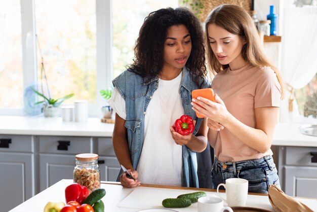 female friends looking for recipe on smartphone while cooking
