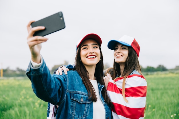 Female friends making selfie in field