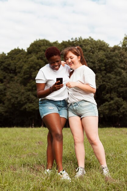 Female friends outdoors looking at smartphone