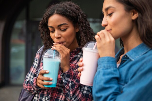 Female friends outdoors together having milkshakes