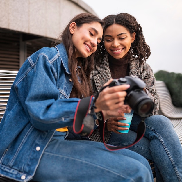 Female friends outdoors together with milkshake and camera