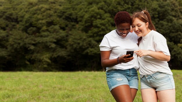 Foto gratuita amici femminili all'aperto con lo smartphone