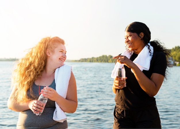 Foto gratuita amici femminili che riposa dopo l'esercizio in riva al lago