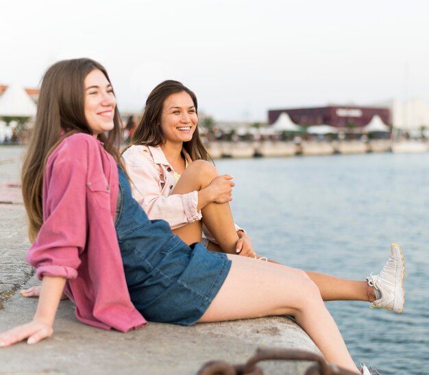 Amici femminili che riposano insieme in riva al lago