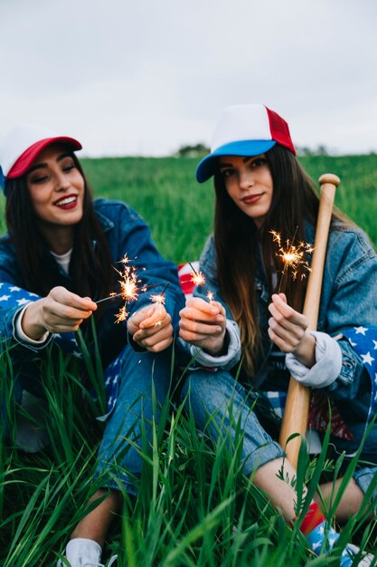 Женщины-друзья, сидящие в поле с американскими украшениями