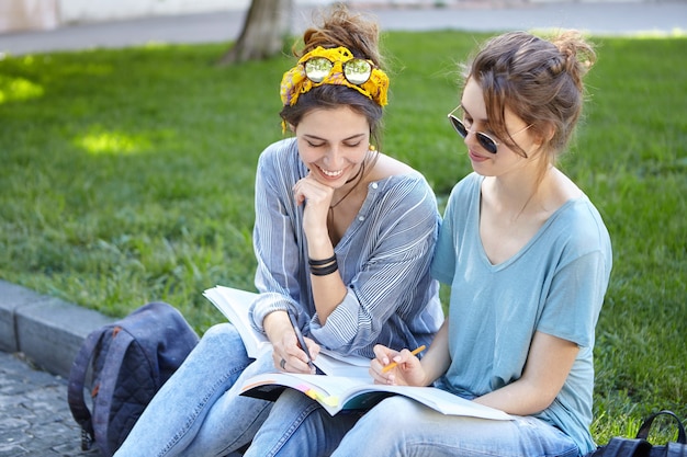 Female friends studying together in park