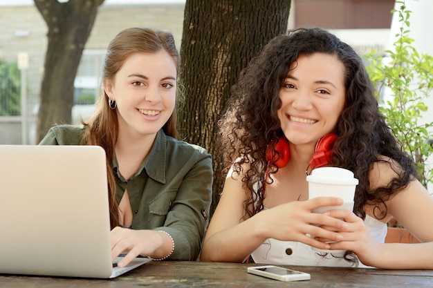 Female friends studying with a laptop in a coffee shop.
