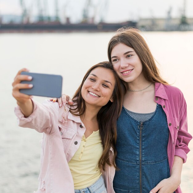 Foto gratuita amici femminili che prendono selfie in riva al lago