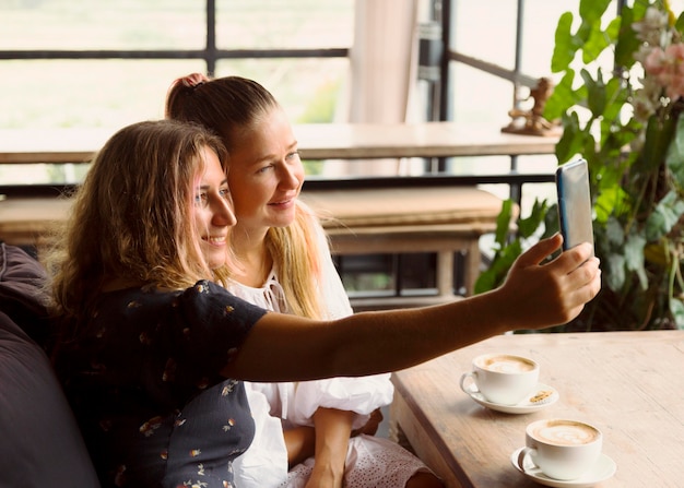 Foto gratuita amici femminili che prendono un selfie mentre beve il caffè