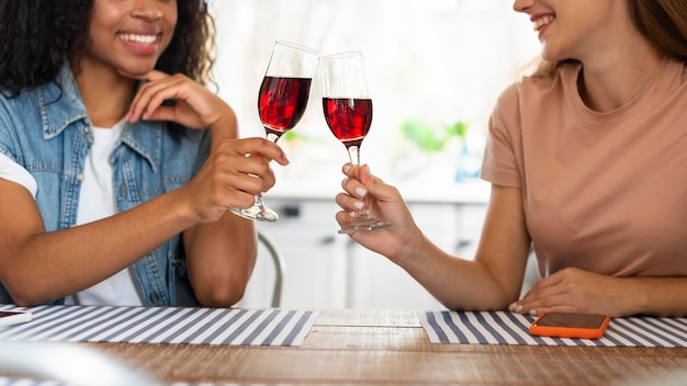 Foto gratuita amici femminili che tostano un bicchiere di vino in cucina