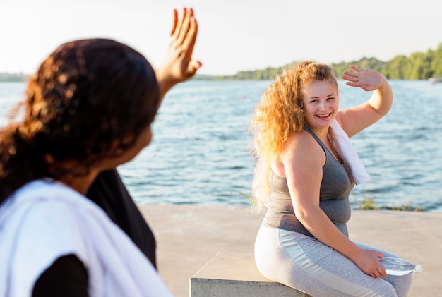 Free photo female friends waving at each other after working out