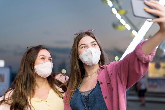 Foto gratuita amici femminili con maschere che prendono selfie al parco di divertimenti