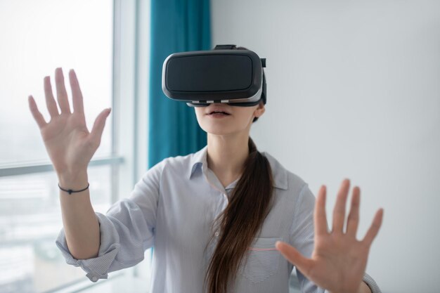 Female gamer in VR glasses standing in a room