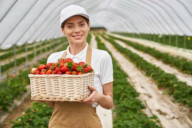 Female gardener holding wicker basket with strawberries