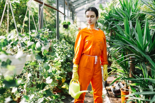 Female gardener with watering can looking at potted plants