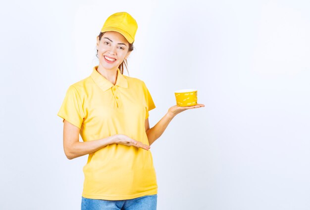 Female girl in yellow uniform holding a yellow takeaway noodle cup . 