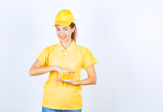 Female girl in yellow uniform holding a yellow takeaway noodle cup . 