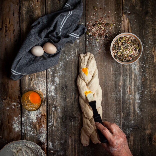 Female glazing dough with mum on wooden table top view