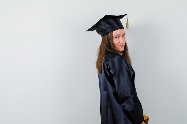 Female graduate looking at camera in academic dress and looking sensible .