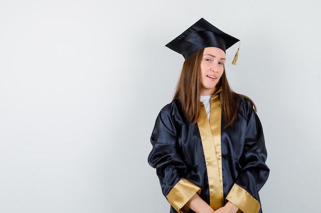 Free photo female graduate posing while standing in academic dress and looking confident , front view.