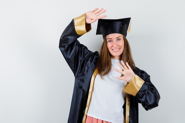 Выпускница-женщина показывает жест стоп в униформе, повседневной одежде и весело выглядит. передний план.
