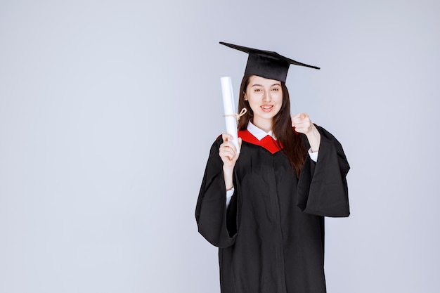 Female graduate student in gown with college certificate standing. High quality photo