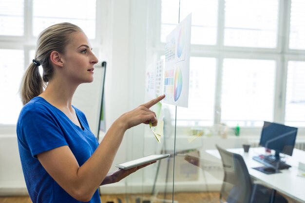 Female graphic designer looking at color chart while holding digital tablet