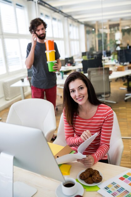 Female graphic designer working over a document while male graphic designer holding plastic containe