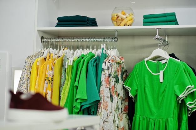 옷가게의 새로운 현대 부티크 봄 여름 드레스 컬렉션의 선반과 선반에 있는 여성용 녹색 다채로운 의류 세트