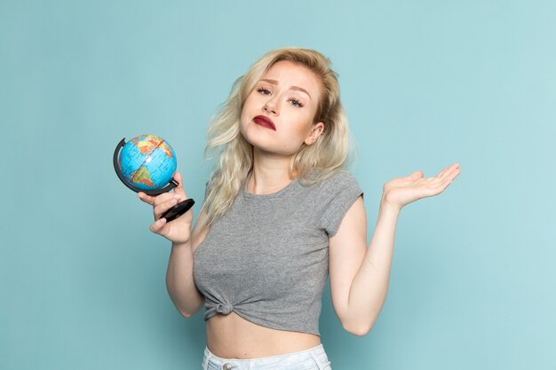 female in grey shirt and bright blue jeans holding little globe