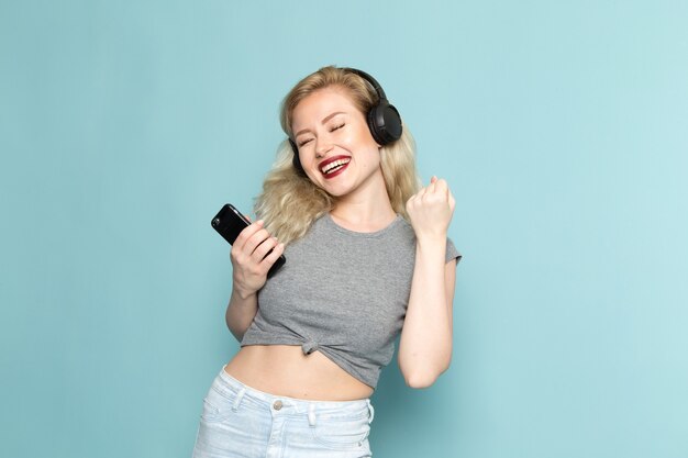 female in grey shirt and bright blue jeans listening to music