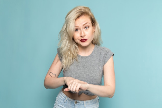 Free photo female in grey shirt and bright blue jeans pointing out into her wrist