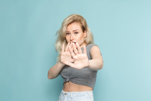 female in grey shirt and bright blue jeans posign with cautious expression