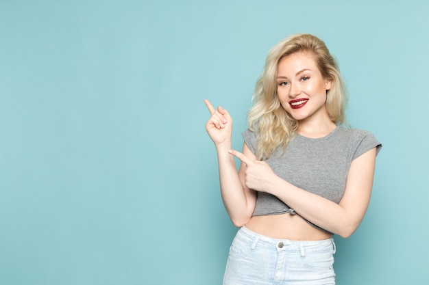 female in grey shirt and bright blue jeans posign with smile