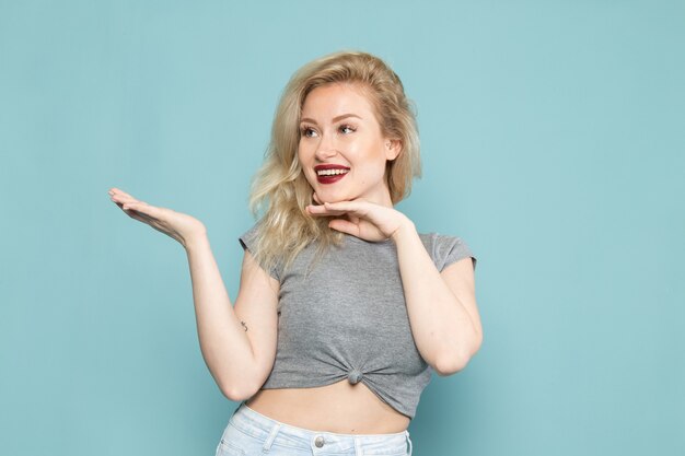 female in grey shirt and bright blue jeans posing with delighted expression