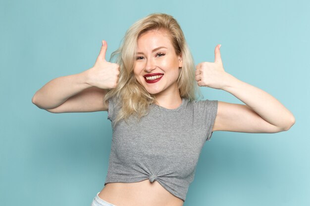 female in grey shirt and bright blue jeans posing with delighted expression