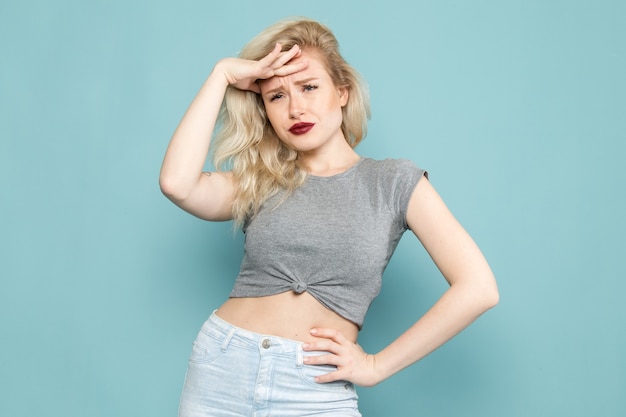 female in grey shirt and bright blue jeans posing with displeased expression