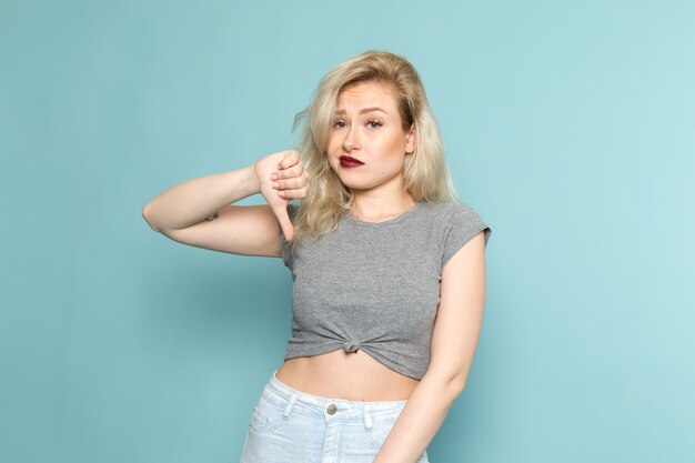 female in grey shirt and bright blue jeans posing with displeased expression