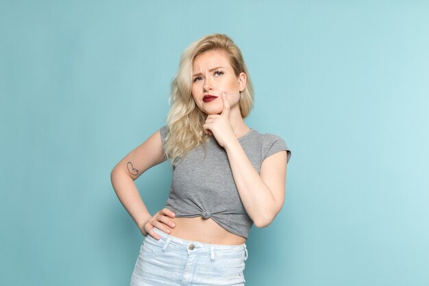 female in grey shirt and bright blue jeans posing with thinking expression